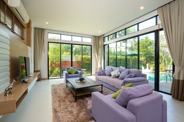 Salon spacieux avec vue sur la piscine et canapé violet