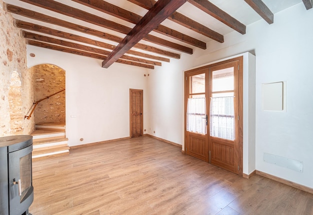 Salon vide d'une maison de ville avec poutres apparentes, parquet et mur de pierre