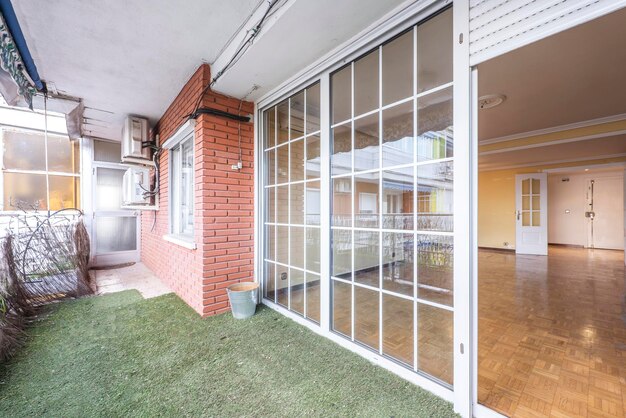 Salon vide avec des meubles avec des planchers en bois, des murs fraîchement peints et un accès à une terrasse avec des murs en briques et des portes en chêne