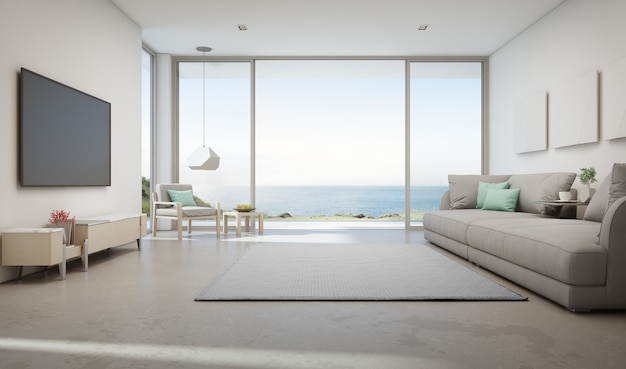 Salon vue mer de la maison de plage d'été de luxe avec grande porte vitrée et terrasse en bois.