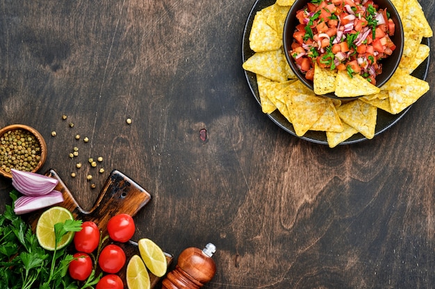 Salsa de sauce tomate mexicaine traditionnelle avec nachos et ingrédients tomates, chili, ail, oignon sur fond de bois sombre et ancien. Concept de cuisine latino-américaine et mexicaine. Maquette.