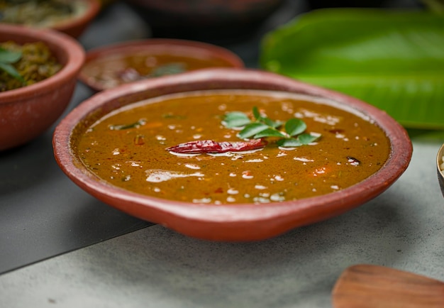 Sambararrangé dans une faïence avec des plats d'accompagnement de fête traditionnels du Kerala disposés en arrière-plan