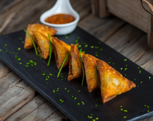 Samboosa ou samosa avec du ketchup servi dans un plat isolé sur la vue de côté de fond en bois