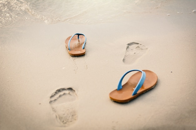 Sandale bleue avec empreinte sur la plage