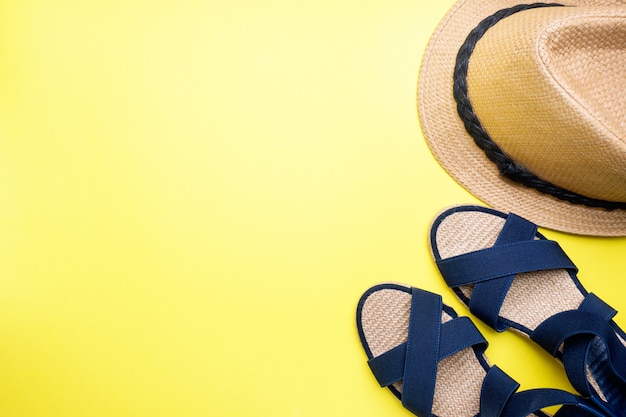 Sandales bleues et chapeau sur fond jaune avec espace de copie. concept vacances d&#39;été. Pose à plat