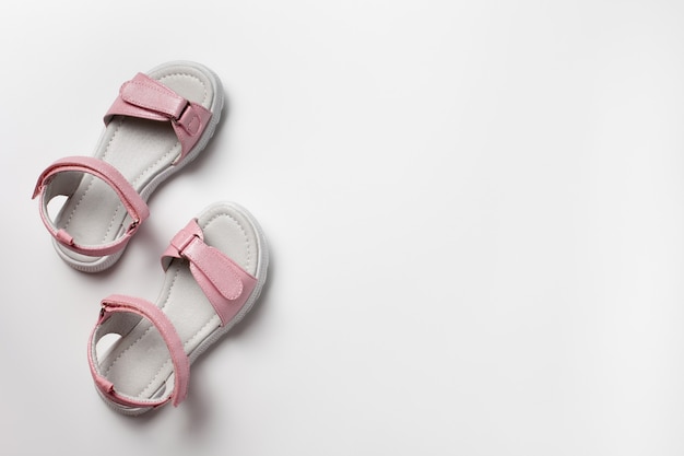 Sandales pour enfants roses en cuir brillant avec fermetures velcro semelles blanches plates isolées sur un fond blanc...