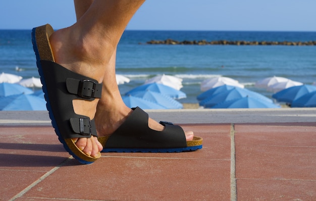 Sandales pour hommes noires et bleues marchant sur la plage pendant les vacances d'été