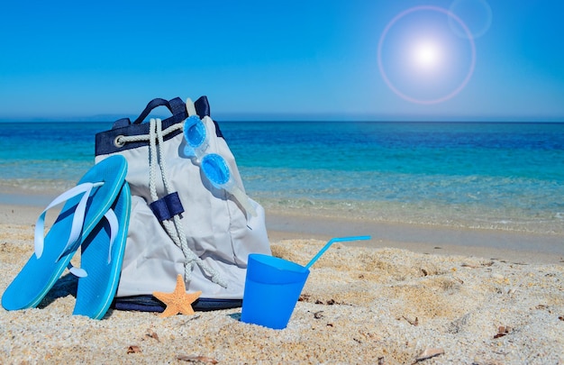 Sandales de sac d'été et boisson sur un rivage blanc