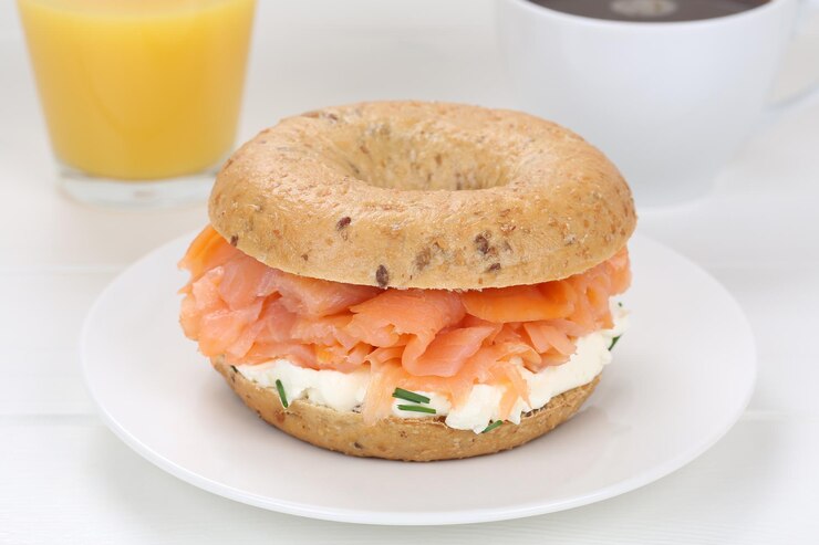 Photo sandwich au bagel pour le petit-déjeuner avec du jus d'orange et du café au saumon