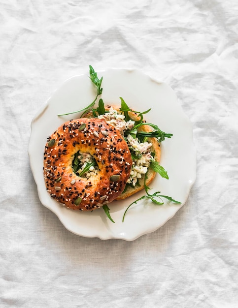 Sandwich au bagel avec salade d'œufs de thon et rogues délicieuse collation de petit déjeuner sur un fond clair vue de haut