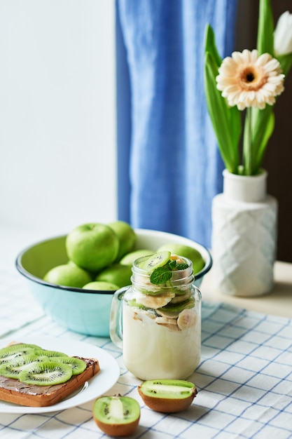 Sandwich au beurre d'arachide et au kiwi, pommes vertes, yaourt à la banane et au kiwi, idée créative pour le petit-déjeuner des enfants, dessert ou repas de vacances, vue de dessus à plat, nourriture saine pour les enfants. Bonjour