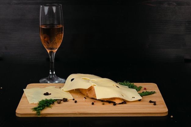 Sandwich au beurre et fromage avec verre de vigne sur une planche de bois