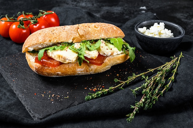 Sandwich au camembert frais, marmelade de poire, ricotta et roquette. Fond noir. Vue de dessus