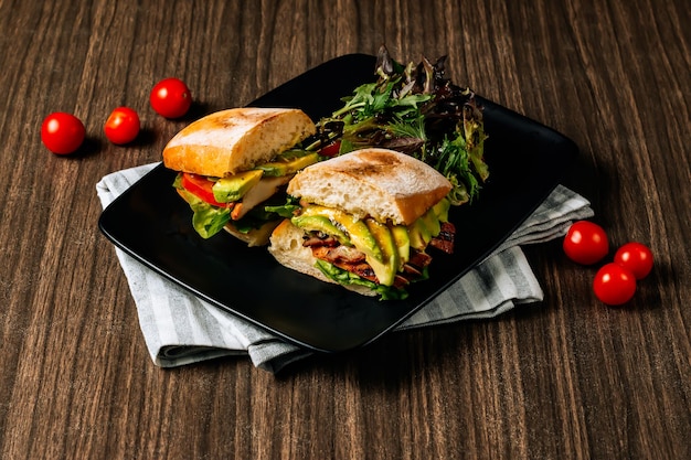 Sandwich au chutney d'avocat et de mangue au poulet fait à la main dans un plateau noir vue de dessus sur une table en bois sombre