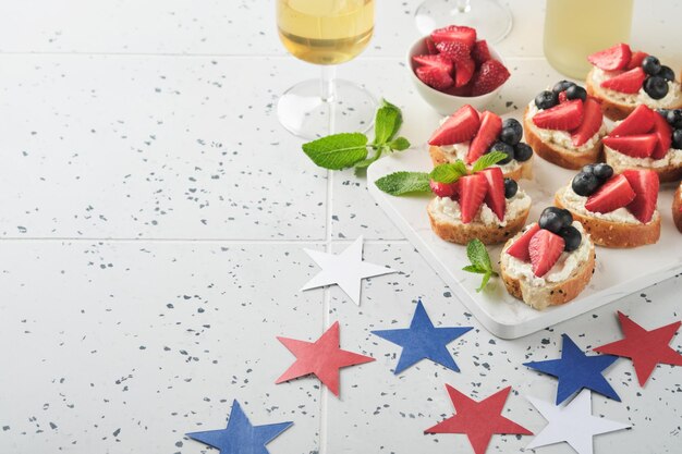 Sandwich au drapeau américain avec des fraises, des bleuets, de la crème battue, du fromage doux sur du pain grillé, nourriture du 4 juillet, la fête de l'indépendance américaine, l'idée du petit déjeuner de la fête patriote.