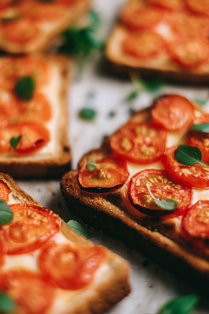 Sandwich au four avec du fromage et des tomates cerises sur du pain noir.