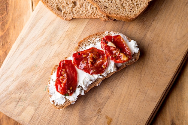 Sandwich au fromage de chèvre tomates séchées au soleil et thym servi sur le plateau sur une surface en bois clair