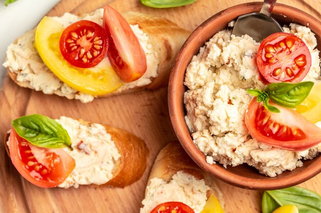 Sandwich au fromage cottage fait maison, tomates cerises et basilic sur une planche en bois. Tendance alimentation saine