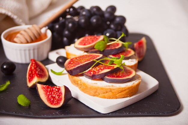 Sandwich au fromage à la crème, figues et miel servi sur la plaque grise sur le blanc. Nourriture saine