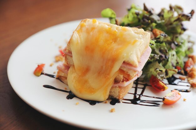 Sandwich au fromage jambon avec salade sur fond de bois