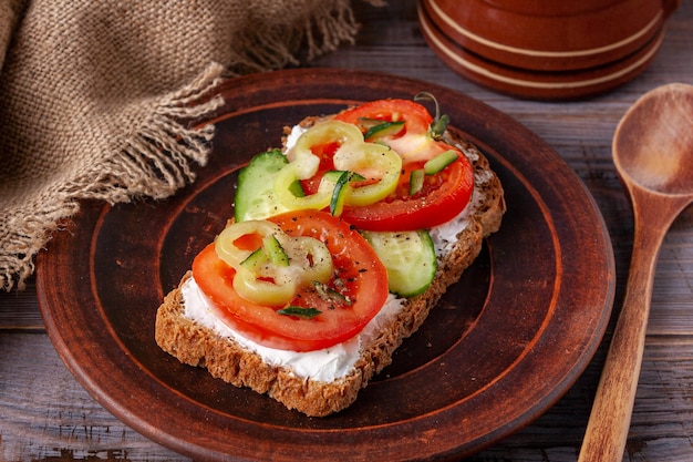 Sandwich au fromage, tomate, concombre et poivre sur une plaque d'argile brune