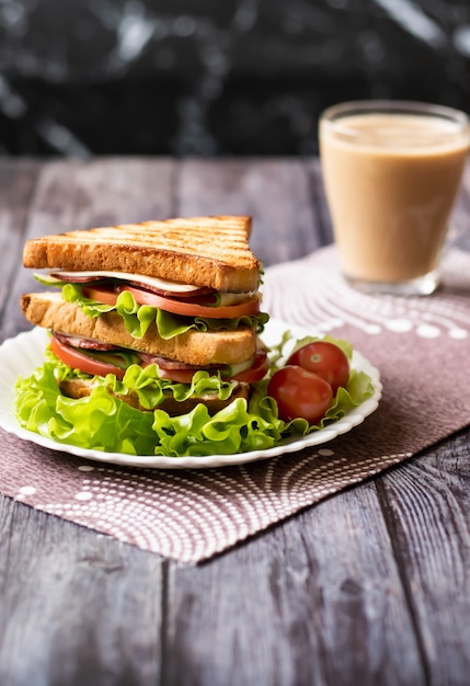 Sandwich au fromage, tomate, concombre, saucisse et laitue sur bois