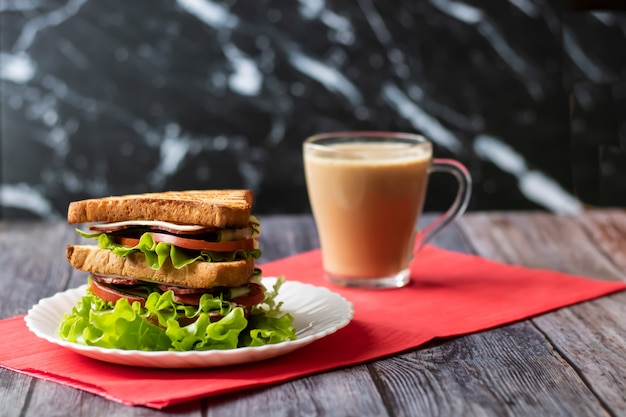 Sandwich au fromage, tomate, concombre, saucisse et salade sur bois