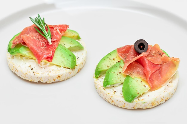 Sandwich au gâteau au riz avec avocado, jambon, olives et romarin