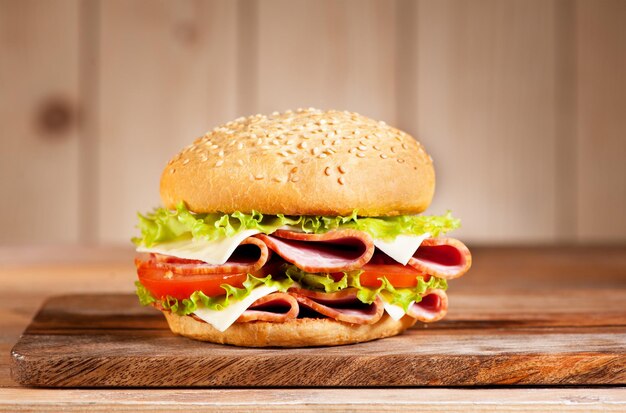 Sandwich au jambon fromage et légumes sur fond rustique