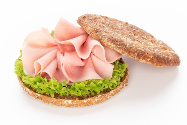 Sandwich au jambon de porc sur une surface blanche.