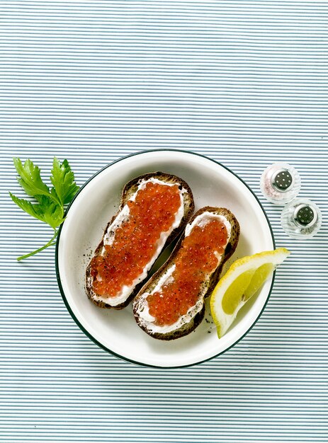 Sandwich au pain frais avec du caviar rouge et du fromage à pâte molle sur une plaque. combinaison classique d'ingrédients.