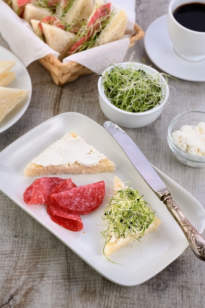 Sandwich au pain grillé au blé avec fromage à la crème avec germes d'oignons microverts et salami