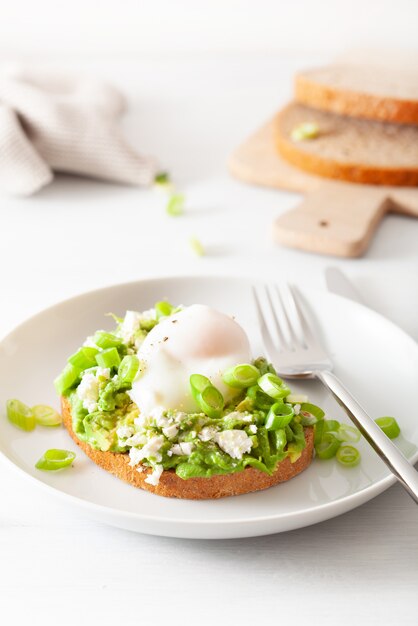 Sandwich au petit déjeuner à l'avocat avec œuf poché et fromage feta