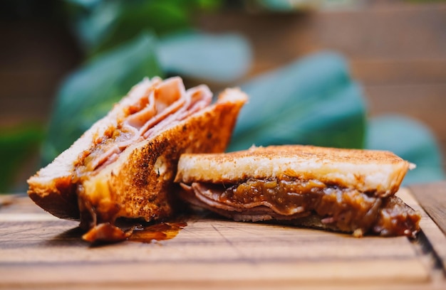 Sandwich au petit-déjeuner avec bacon, fromage et sauce tomate sur planche de bois