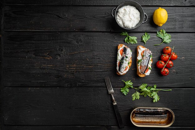 Sandwich au poisson fumé, sur fond de table en bois noir, vue de dessus à plat, avec espace de copie pour le texte