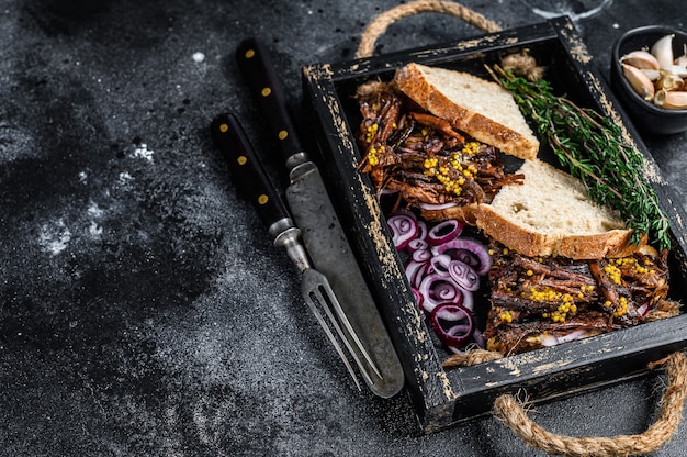 Sandwich au porc effiloché avec de la viande de porc fumée dans un plateau en bois