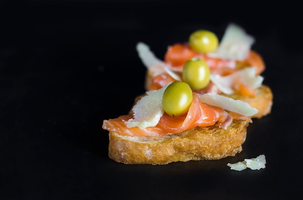 Un sandwich au saumon frais avec du fromage sur fond noir.