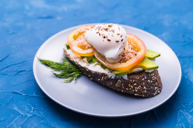 Sandwich au saumon fumé, oeuf et avocat sur surface bleue, vue du dessus. Concept pour la santé