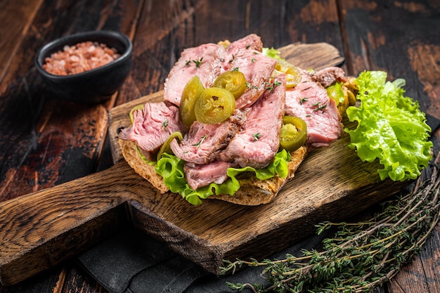 Sandwich au steak de boeuf avec salade de boeuf grillée en tranches et légumes sur pain Fond en bois Vue de dessus