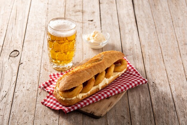 Sandwich aux anneaux de calamars avec de la bière sur la table en bois. Cuisine espagnole typica