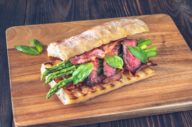 Sandwich aux asperges et tranches de steak de boeuf sur la planche de bois