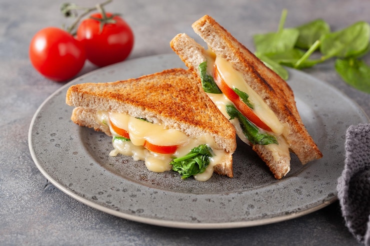 Photo sandwich aux épinards et tomates au fromage grillé sur fond de béton