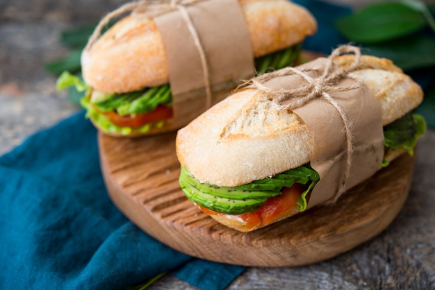 Sandwich aux légumes maison avec fromage à la crème, avocat frais et tomates sur une table en bois. Photo horizontale. Mise au point sélective.
