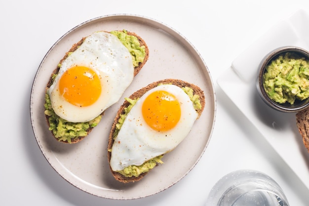 Sandwich aux œufs d'avocat avec un verre d'eau. Concept de petit-déjeuner léger et sain. Toasts de grains entiers avec