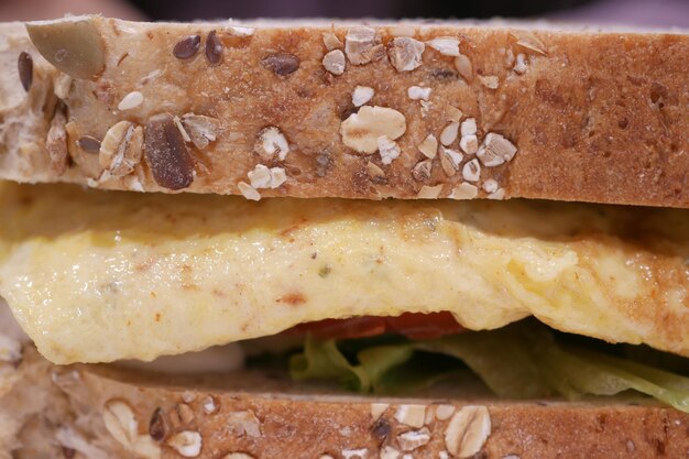 Sandwich aux œufs fait avec du pain brun, de la tomate et de la laitue sur la table