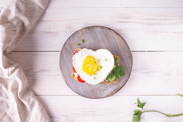 Photo sandwich aux oeufs en forme de coeur sur planche de bois