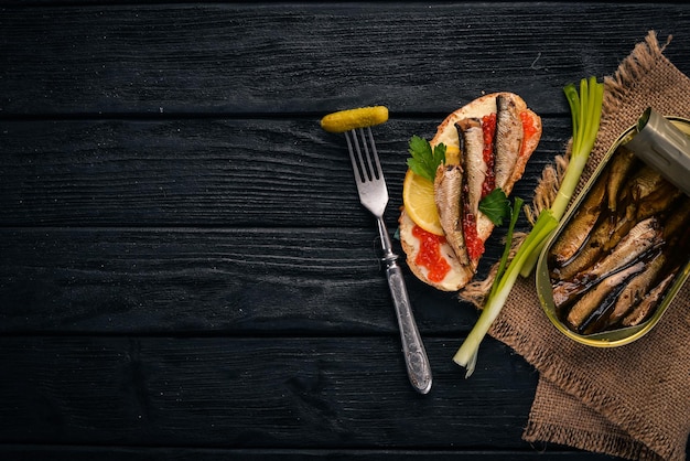 Sandwich aux sprats et oignon caviar sur fond de bois Vue de dessus Espace de copie