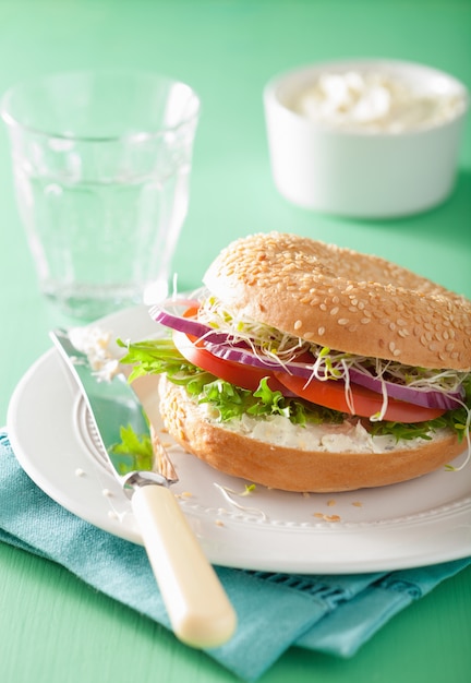 Sandwich aux tomates sur bagel avec fromage à la crème, oignon et laitue