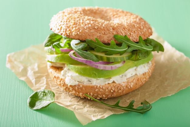 Sandwich à l'avocat sur bagel avec roquette concombre oignon fromage frais