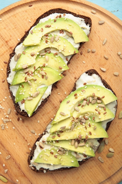 Sandwich à l'avocat sur du pain de seigle noir fait avec des avocats en tranches fraîches sur table brune. Vue de dessus